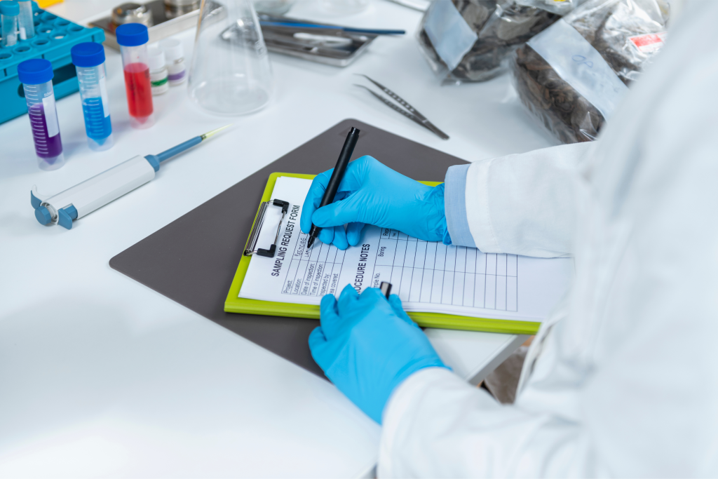 Technician in a laboratory setting writing on a tablet for a hemp COA. 