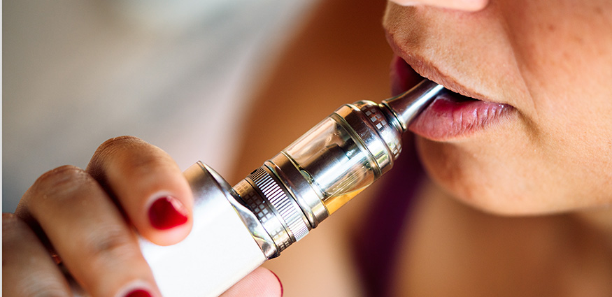 Person inhaling from an electronic vaping device for nicotine.