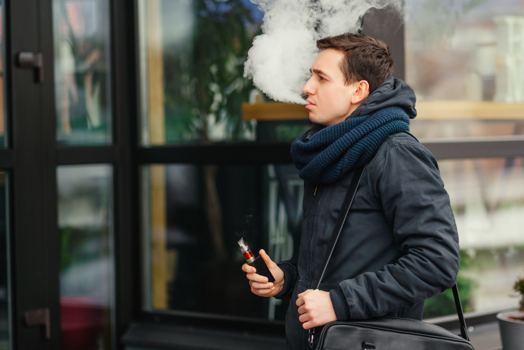 Person walking down the street and using a nicotine vaping device.